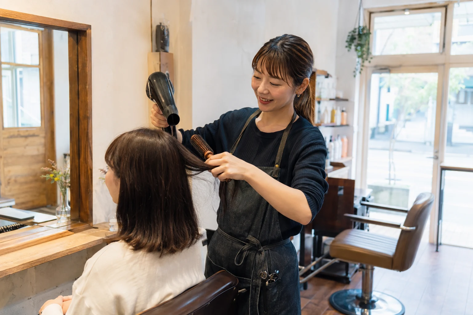 地域の美容室で来店客の髪を乾かす美容師(AI生成イメージ)