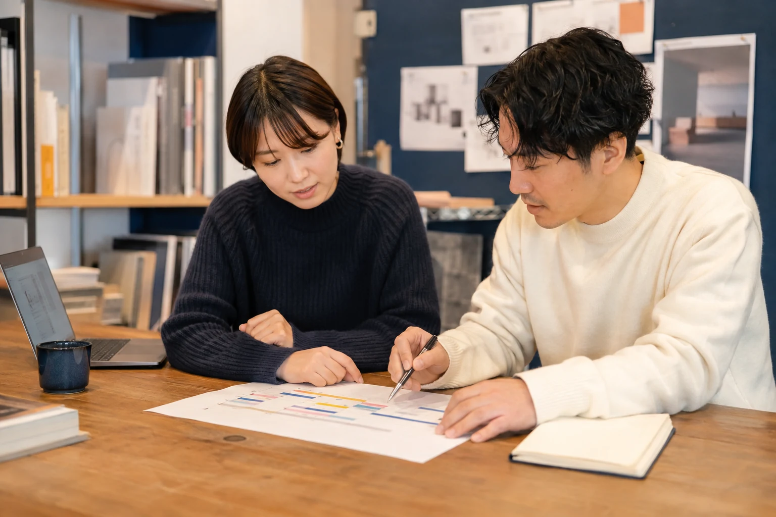 制作予定と作業時間を確認する小さなデザイン事務所の2人(AI生成イメージ)