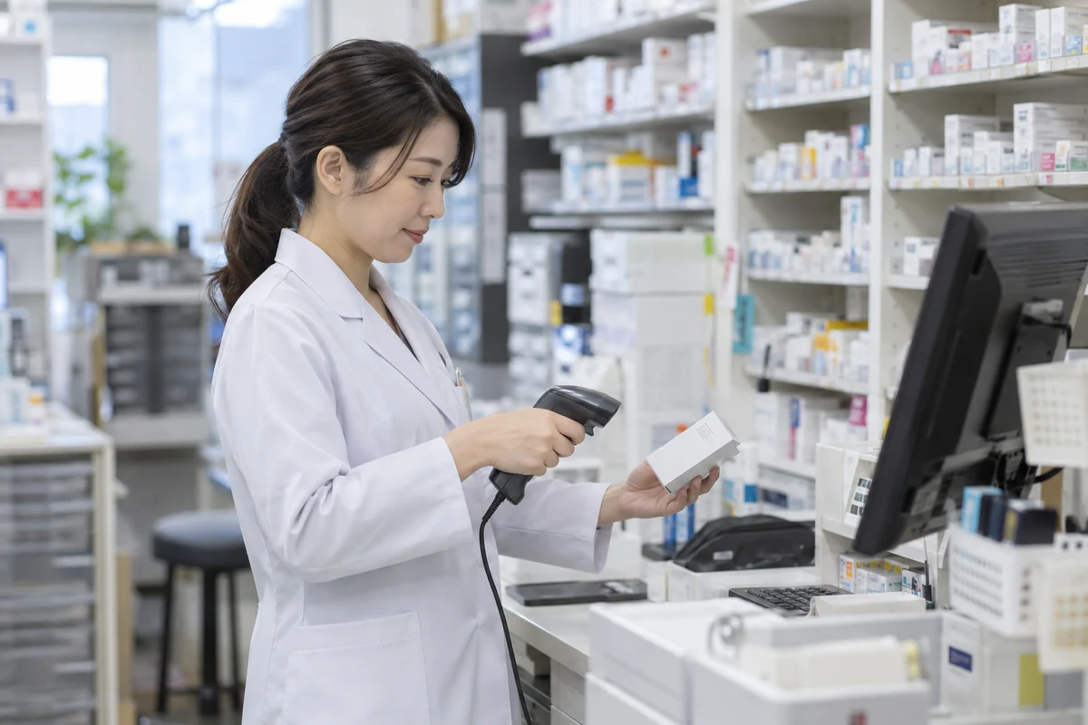 薬剤師が医薬品の箱を読み取り、薬局の在庫を確認する仕事の場面(AI生成)