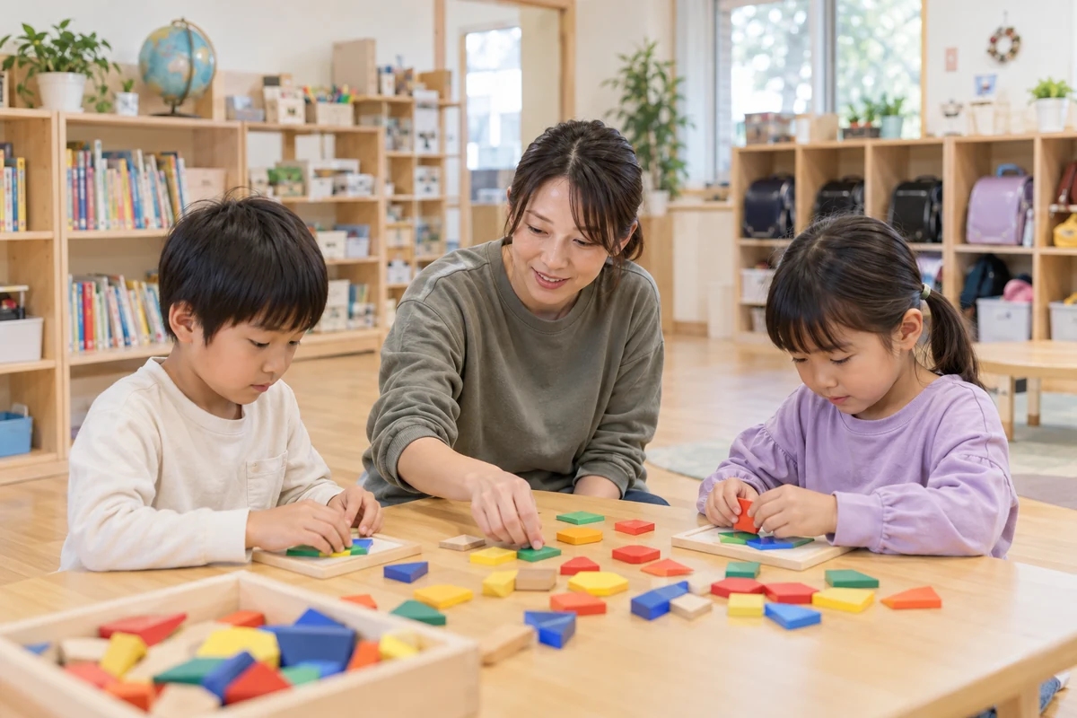 民間学童の室内で職員が子ども二人の木製教材を使った活動を見守る架空の仕事場面
