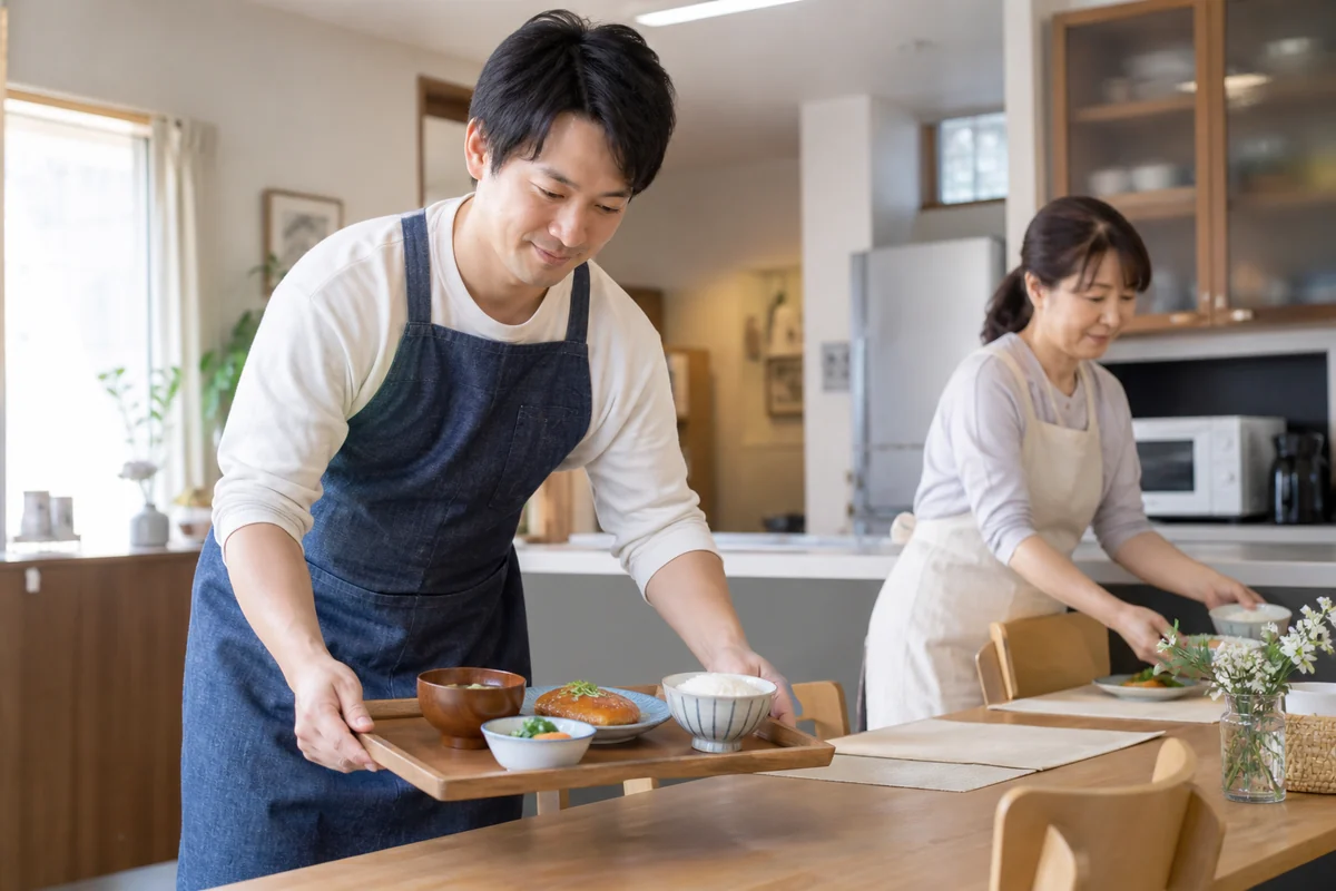共同生活の住まいで食事と配膳を準備する支援スタッフを表したAI生成の架空イメージ